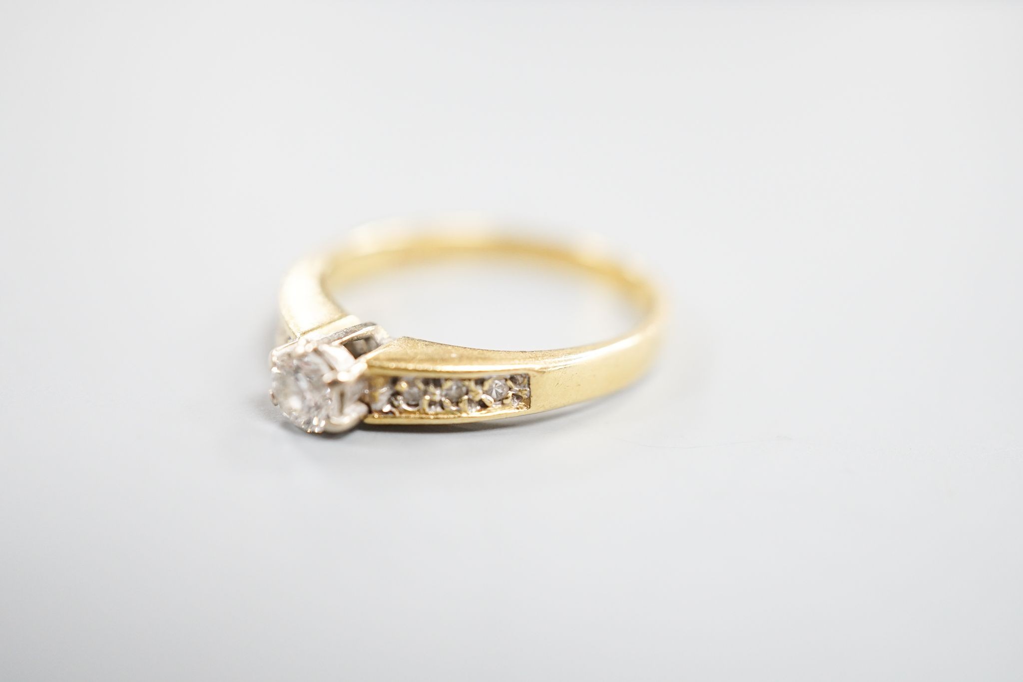 A modern 18ct gold and single stone diamond ring, with diamond set shoulders, size L, gross 2.4 grams.